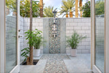 Biophilic outdoor bathroom featuring pebble tile floor and wall