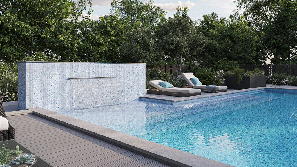 Modern outdoor pool area with a white cascading water wall, lounge chairs, and lush greenery in the background, enhanced by the subtle beauty of mosaic tiles.